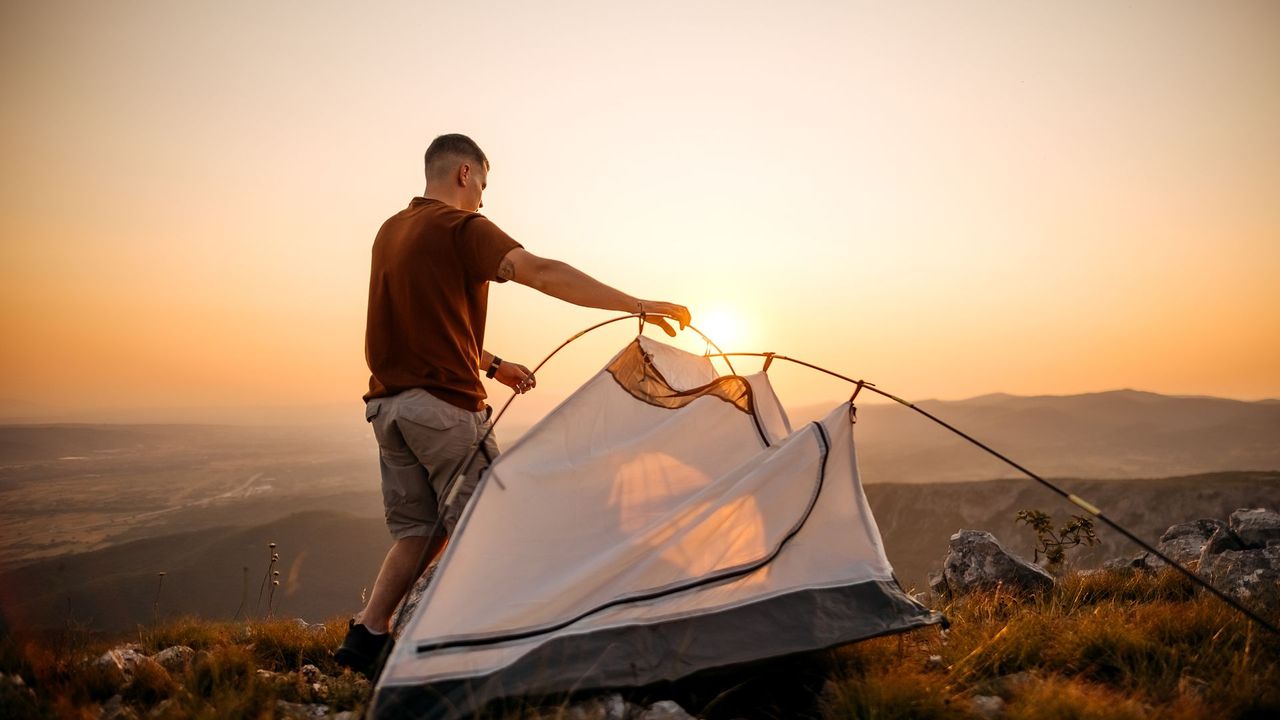 A man setting up his tent on a hill