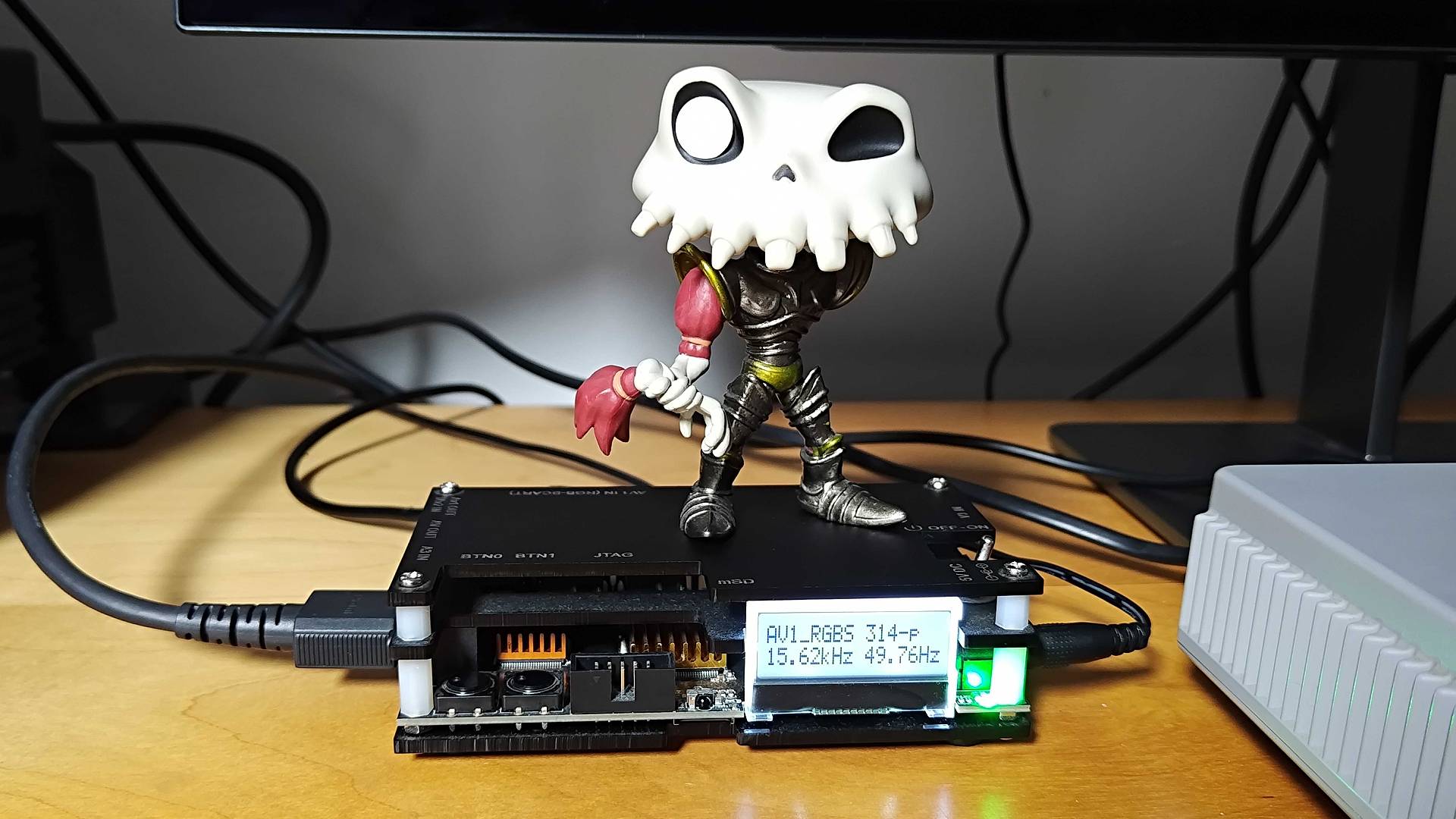 OSSC upscaler with Sir Dan MediEvil figure on top and screen illuminated with video information.