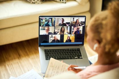Symbolizing remote work or a remote job, a businesswoman meets with colleagues on a video call or web conference. She is working from home.