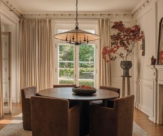 dining room with white walls and white drapes and round wooden table and large pendant light