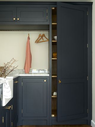 laundry room with blue cabinets and hanging rail by Olive & Barr