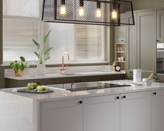 A neutral kitchen with overhead lights and quartz countertop