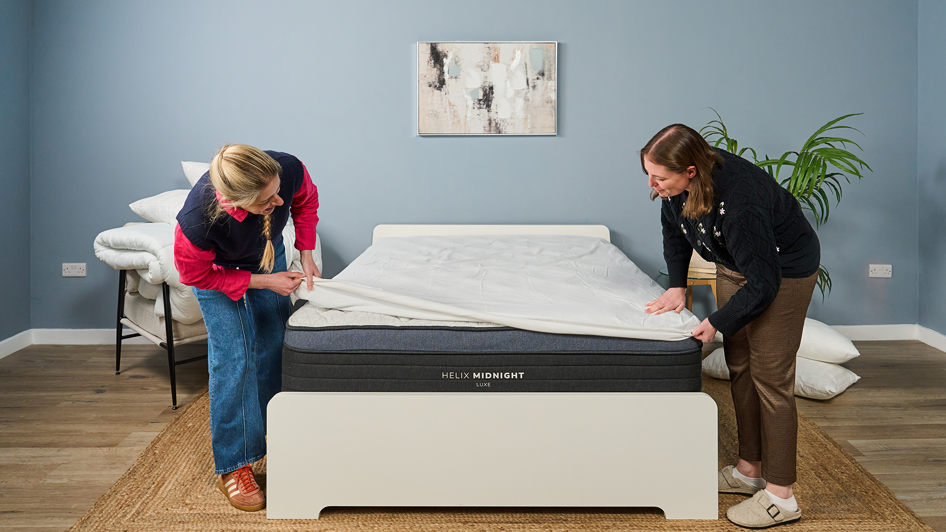Two Tom's Guide mattress testers cover the Helix Midnight Luxe with a white mattress protector to keep it clean after testing
