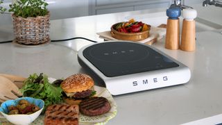 Smeg portable induction cooktop with a range of cooked food to the side