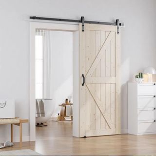 A wooden barn door in a white room