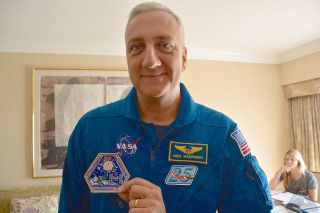 Mike Massimino holds up a mission patch for his fictional flight to the International Space Station, as was part of his storyline on the CBS comedy "The Big Bang Theory."