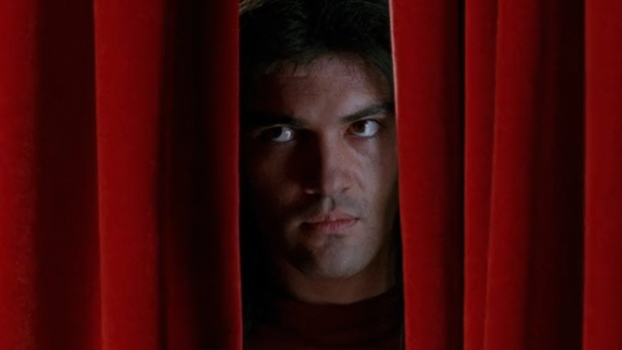 Antonio Banderas peaking through a curtain in Tie Me Up! Tie Me Down