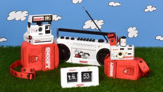 Group shot of Retrospekt Snoopy collection on grass with cartoon clouds on blue sky background