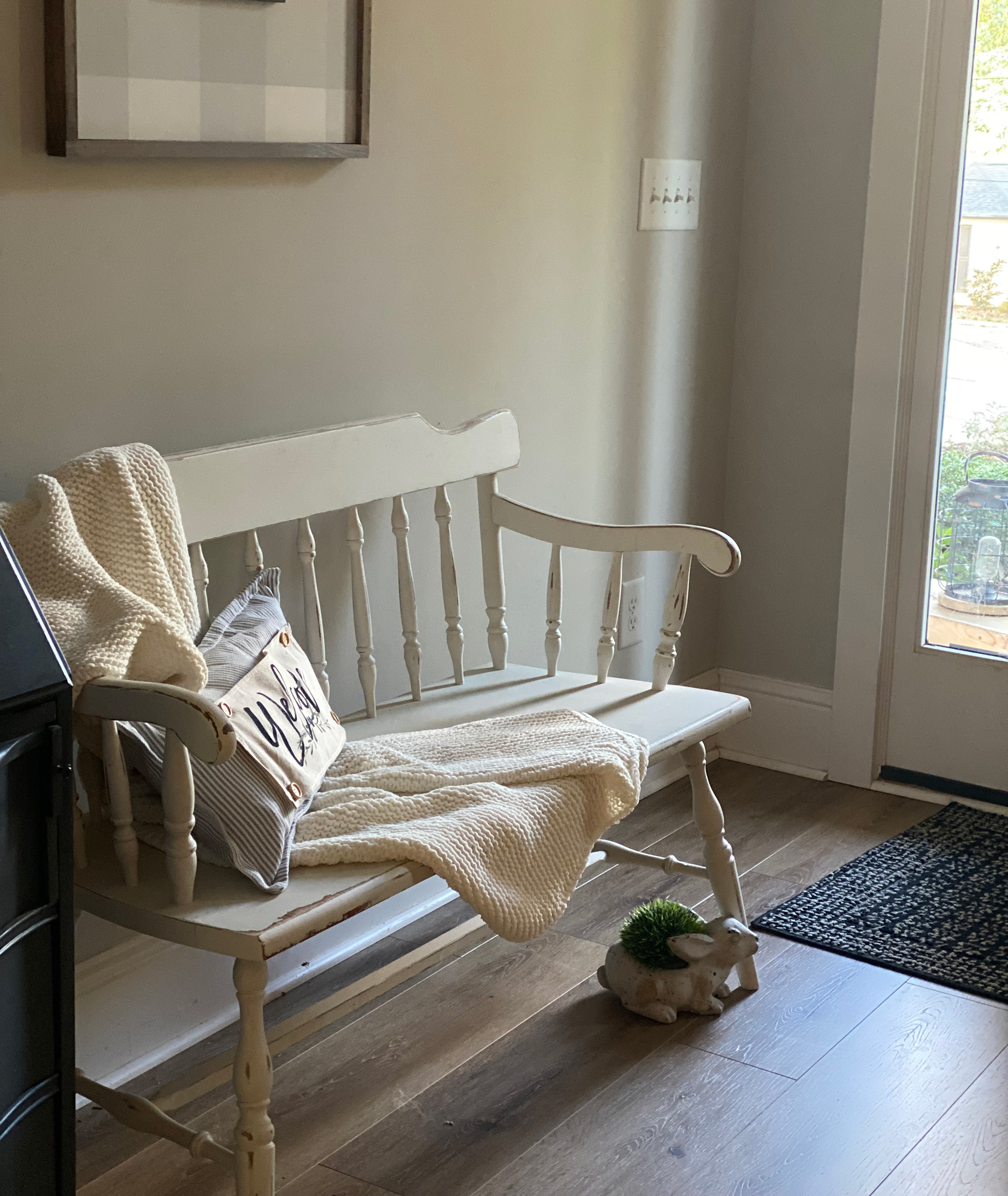 White wooden entryway bench in foyer with wooden flooring