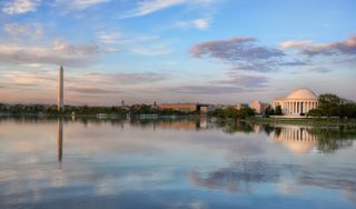 The Washington and Jefferson Monuments at sunrise with clouds reflected in the water