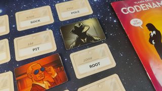 A close up of Codenames cards, with the Assassin in the center of a grid