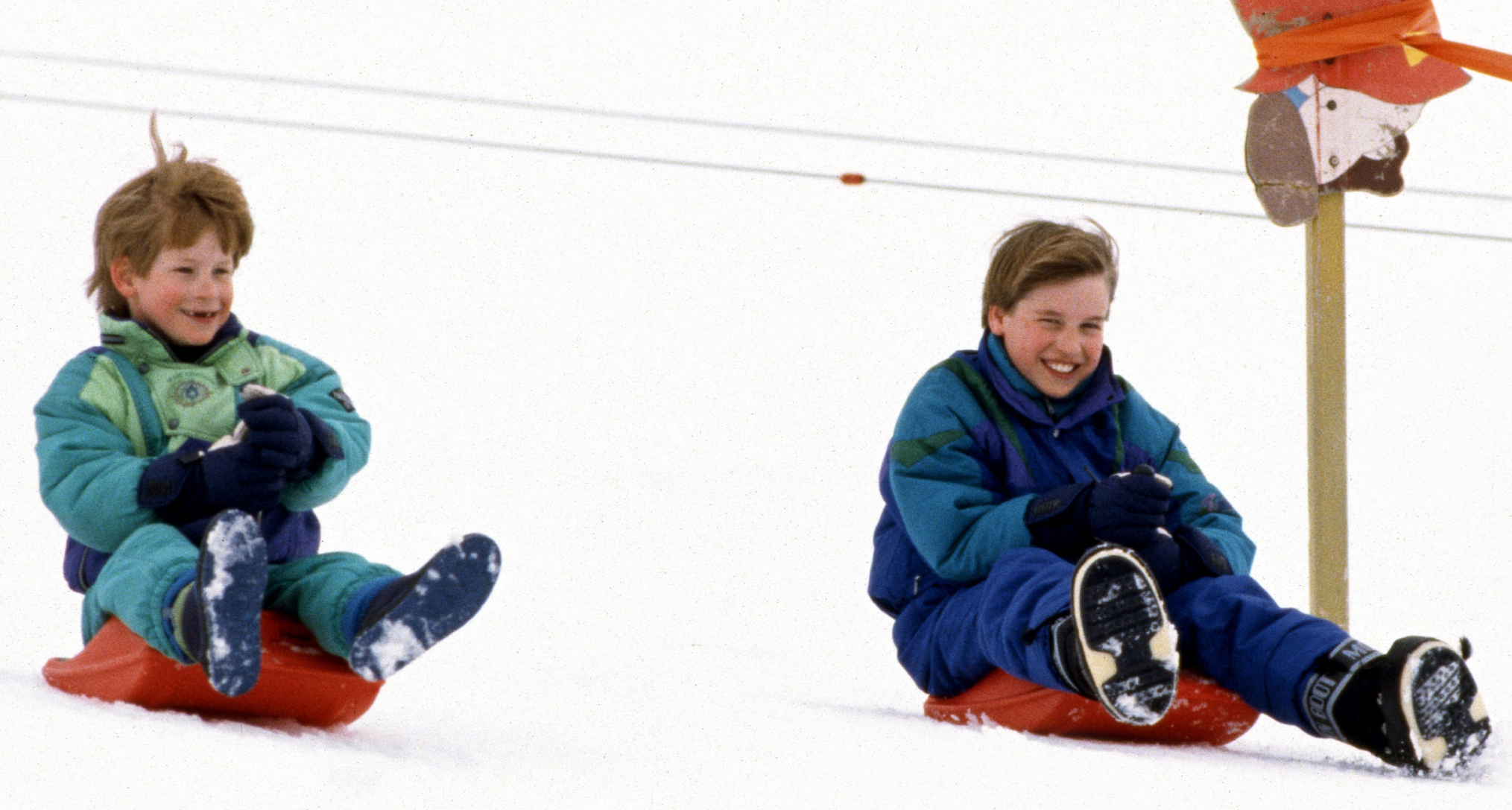 Prince Harry and Prince William sledding down a hill
