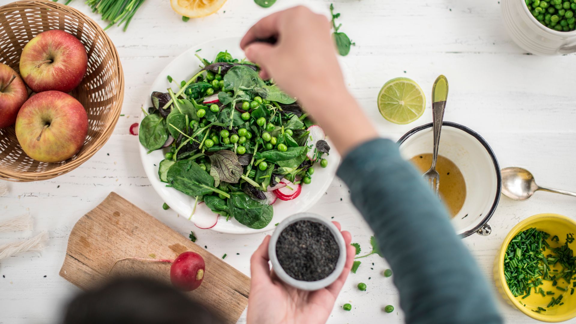 hand scattering spice over salad