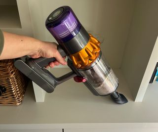 The Dyson V15s Detect Submarine in handheld mode, cleaning a bookshelf