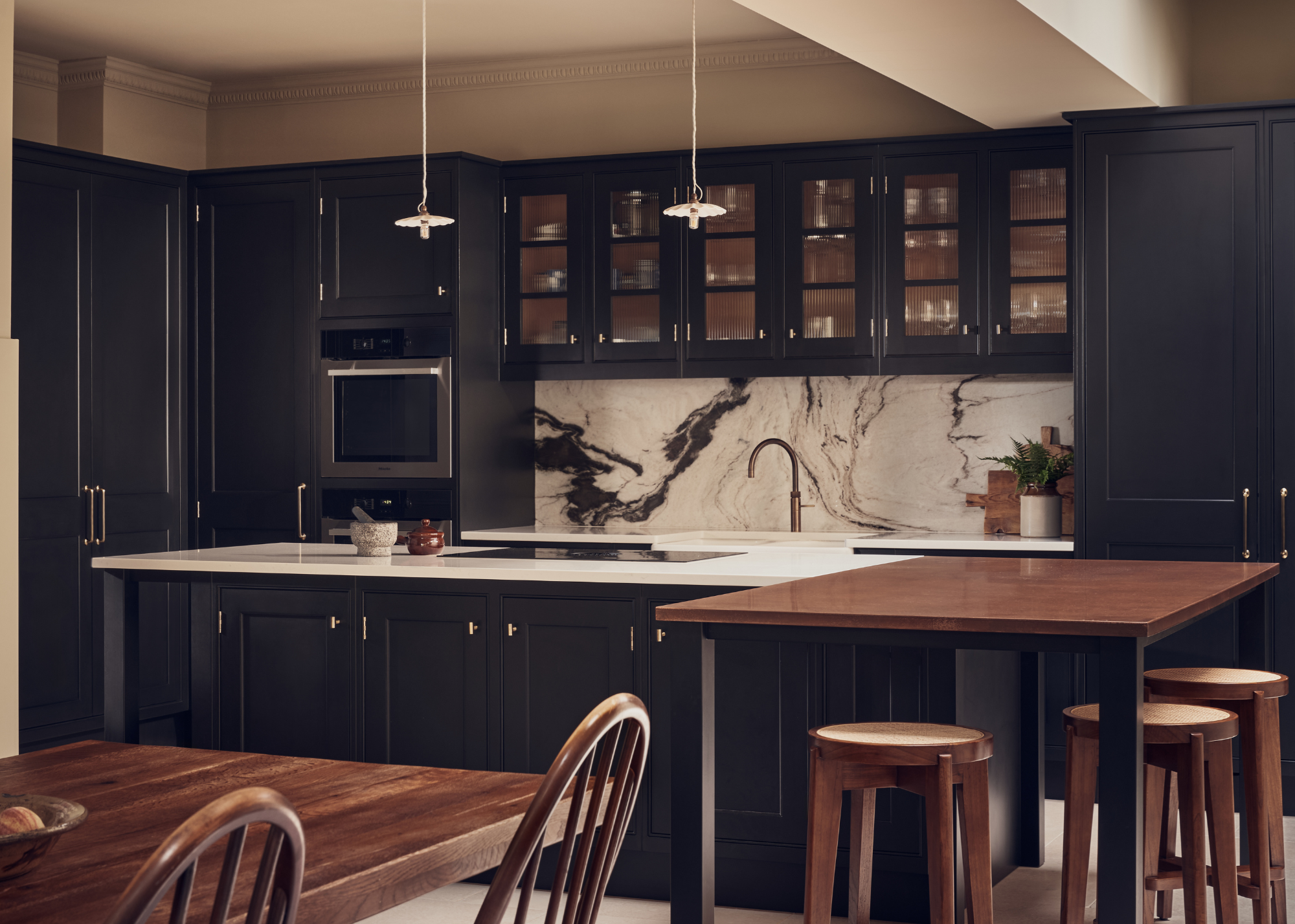 open plan kitchen with dark blue cabinetry, glass-fronted upper cabinets, and a split kitchen island