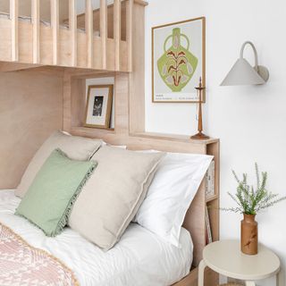 double bed with pink and green cushions next to small bedside table