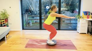 Woman performs a squat on a wobble board