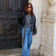 Influencer @deborabrosa wears slouchy jeans and suede loafers with a grey jumper and a black leather jacket.