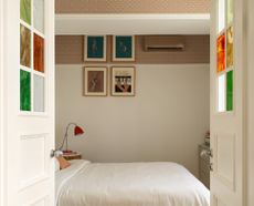 A small bedroom with stain glass doors and a white bed