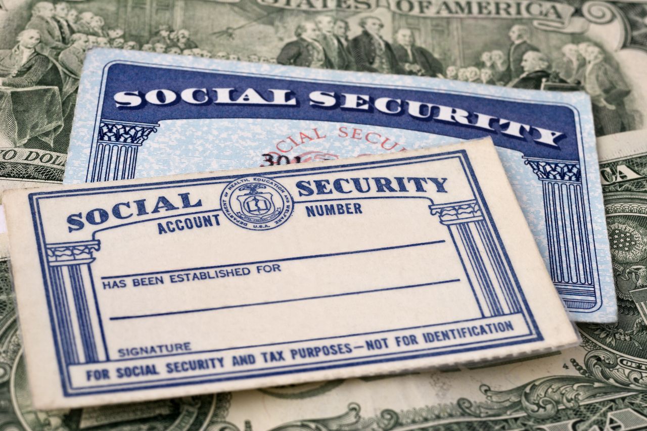 Close up photograph of Social Security cards against currency background, selective focus.