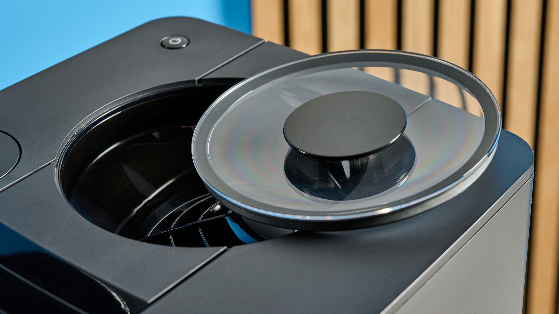 the jura c8 automatic coffee machine in piano black photographed with a blue and wood background