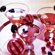 Christmas gifts for foodies filled cocktail glasses beside an assortments of baubleswith edible flowers