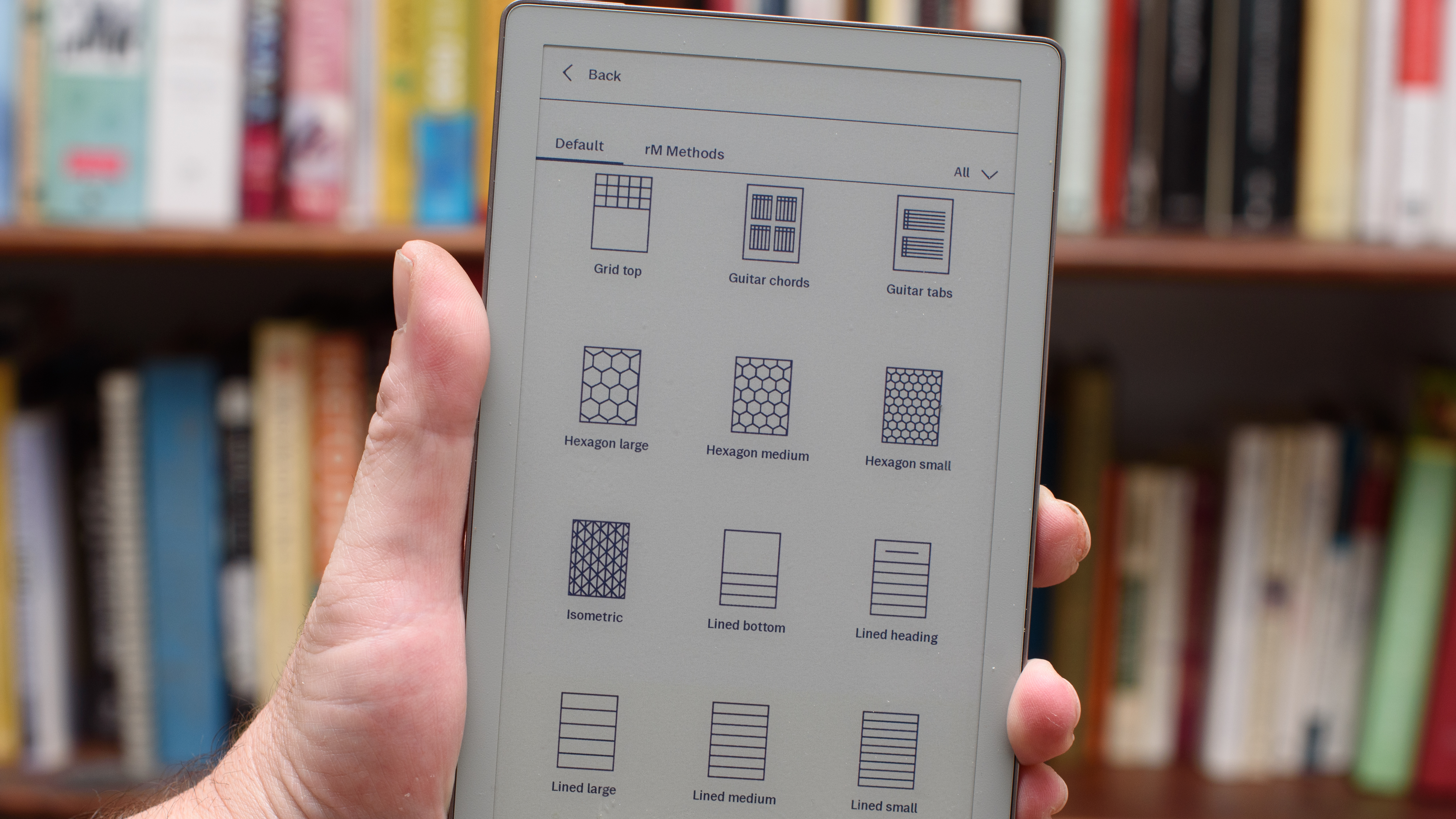 reMarkable Paper Pro Move tablet in front of a library of books, showing various writing screens and comparing the size to a Moleskine notebook