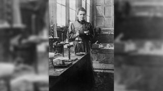 Black and white image of Marie Curie standing in her lab