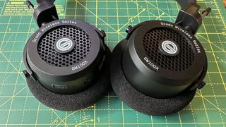 Grado's GW100x headphones in a green-walled room, on a wooden desk with cutting mat.