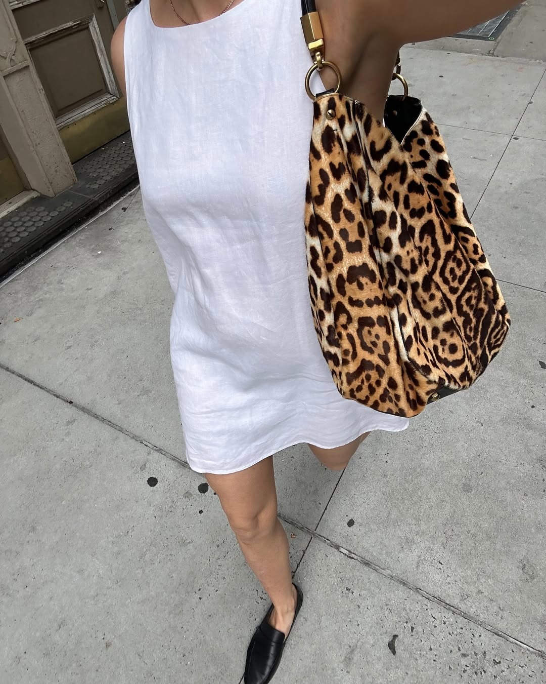 Influencer Anna wears a white linen shift dress with loafers and a cheetah print bag.
