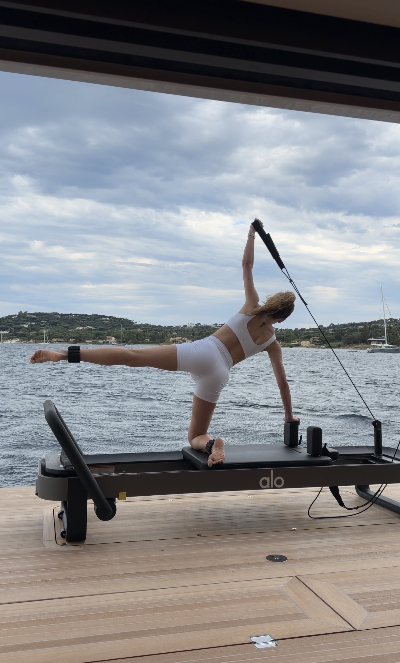 Eliza Huber wearing a white Alo workout set on the reformer on the Alo yacht.