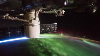 A photograph of a magenta and green aurora captured from the international space station
