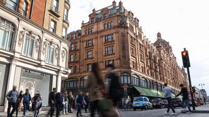 Pedestrians crossing street in front of Harrods luxury department store in London, United Kingdom.