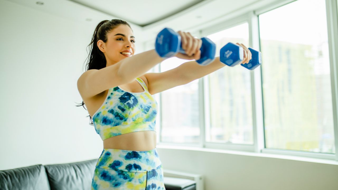 A woman completing an upper-body dumbbell workout at home