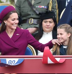 Princess Kate putting her hand on Princess Charlotte's shoulder sitting at VE Day event