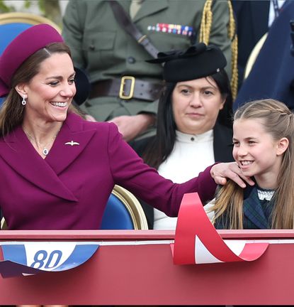 Princess Kate putting her hand on Princess Charlotte's shoulder sitting at VE Day event