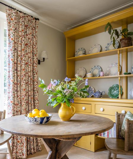 A yellow hutch displaying blue kitchenware