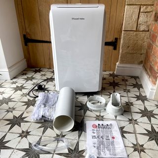 The Russell Hobbs RHPAC11001 Portable Air Conditioner unboxed on a tiled floor with geometric star design