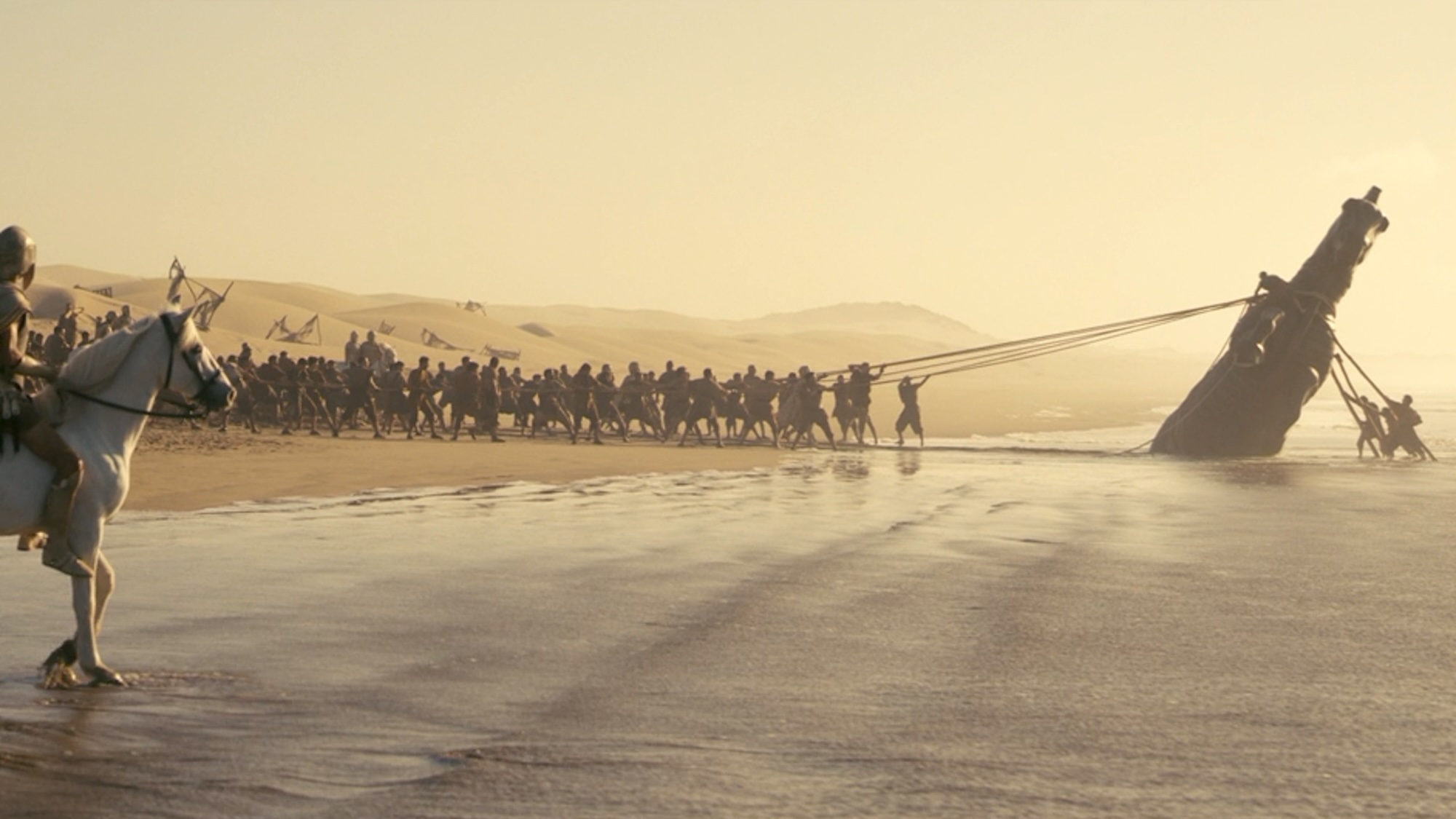 The Trojan Horse being hauled upright on the beach in The Odyssey