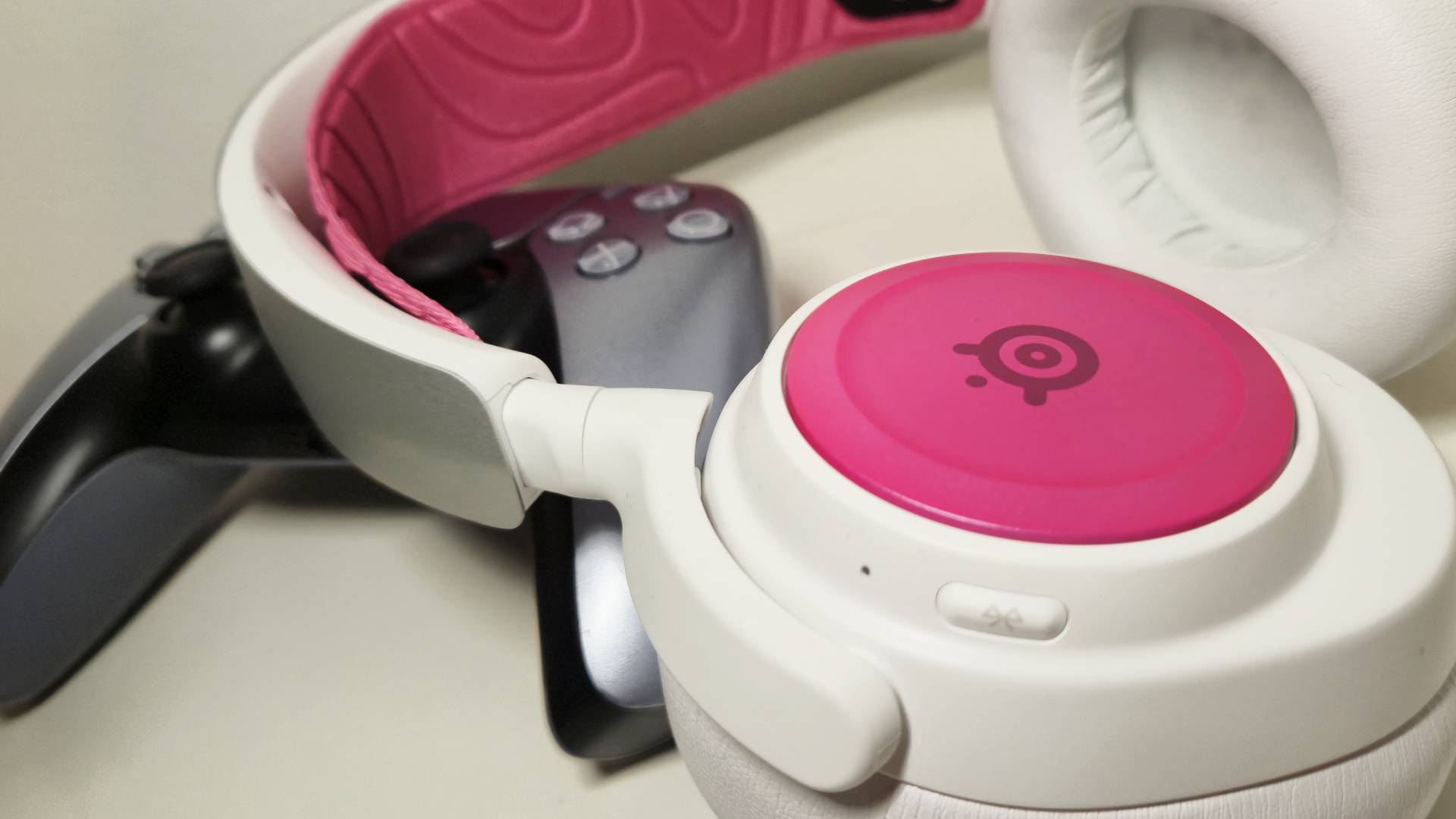 Photo of the SteelSeries Arctis Nova Pro Wireless sitting on a PS5 DualSense controller.