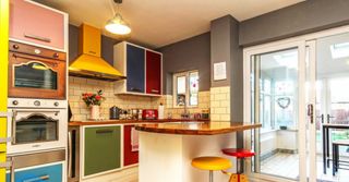 A kitchen with wooden island and colourful cabinets