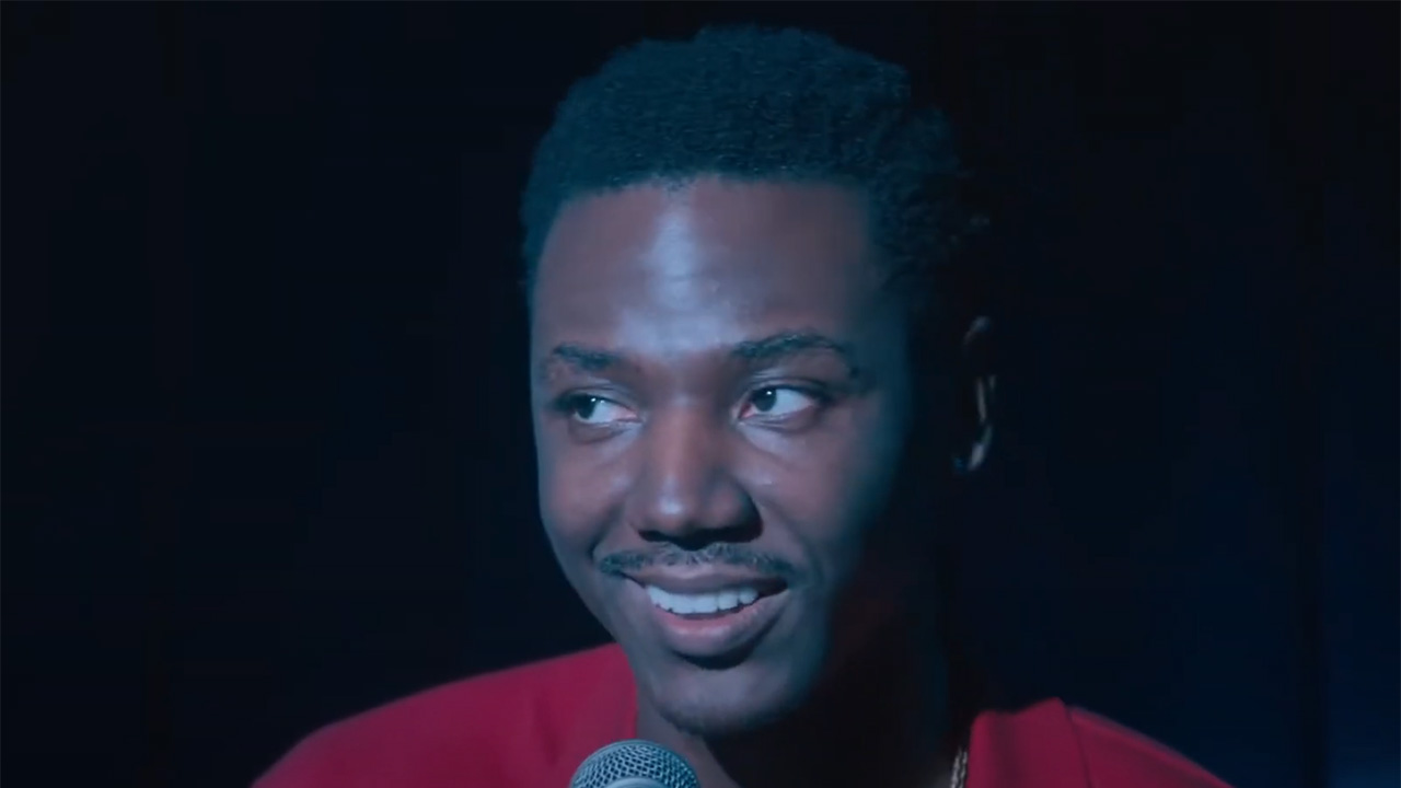 Jerrod Carmichael speaks onstage in Rothaniel with a smile on his face.