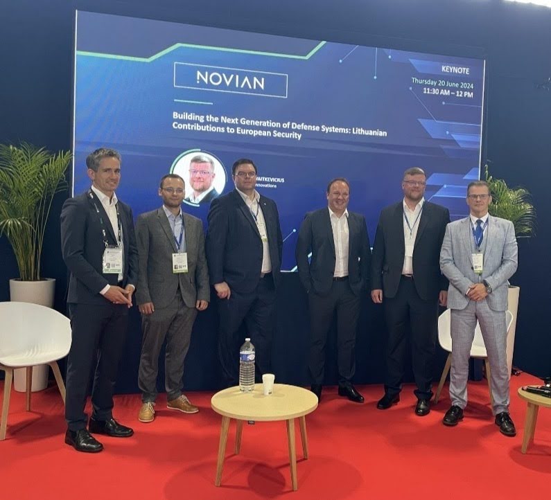 Six men in suits standing in front of a projector screen that says NOVIAN.