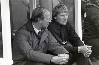 Newcastle United manager Jack Charlton (l) and coach Willie (Iam) McFaul look on from the bench before a match against Luton Town at St James' Park on February 23rd, 1985 in Newcastle upon Tyne, England.