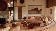 70s style living room with curved sofa around a nesting coffee table, shag rug, and brick fireplace with two armchairs in front of it 