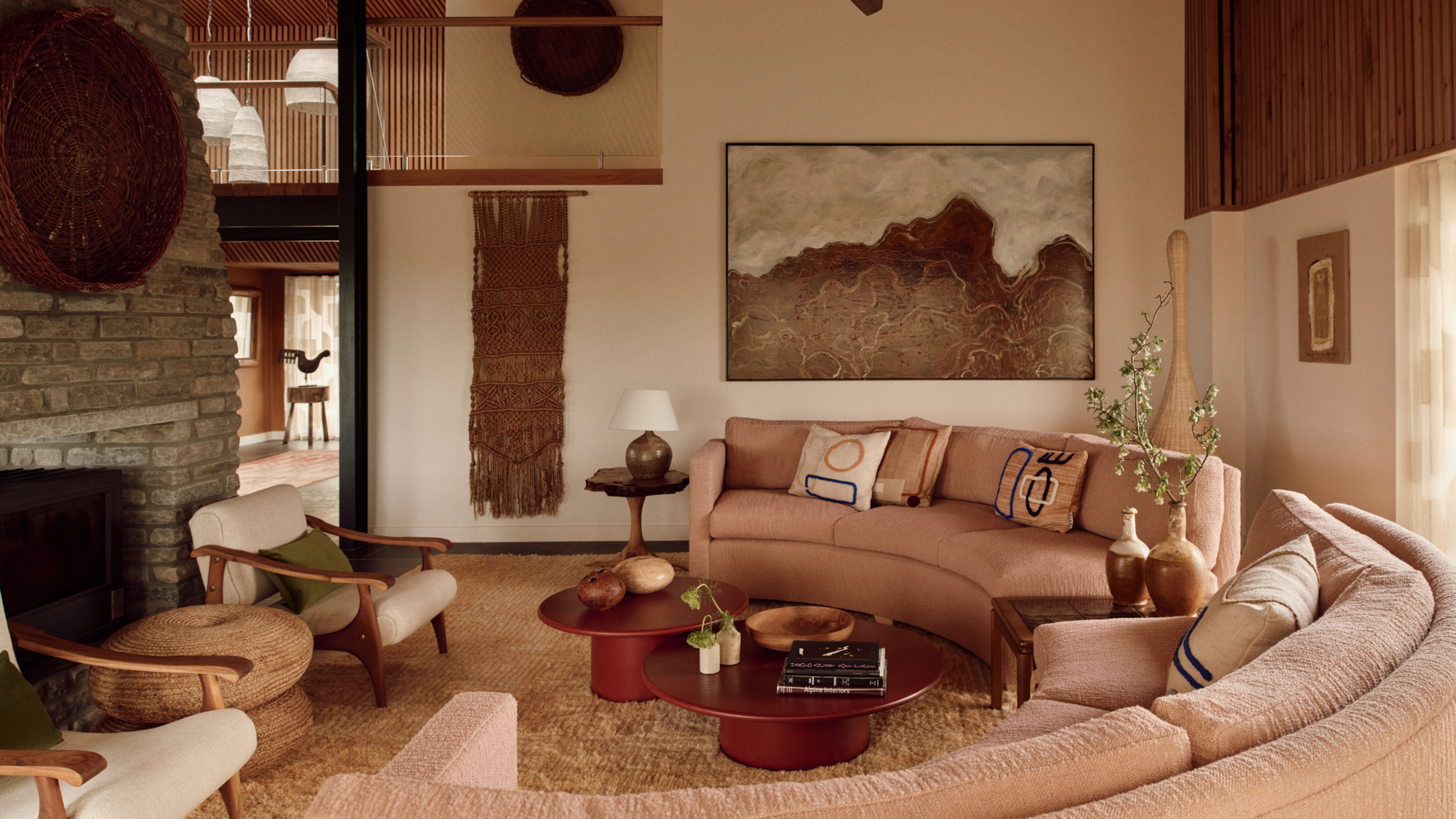 70s style living room with curved sofa around a nesting coffee table, shag rug, and brick fireplace with two armchairs in front of it 