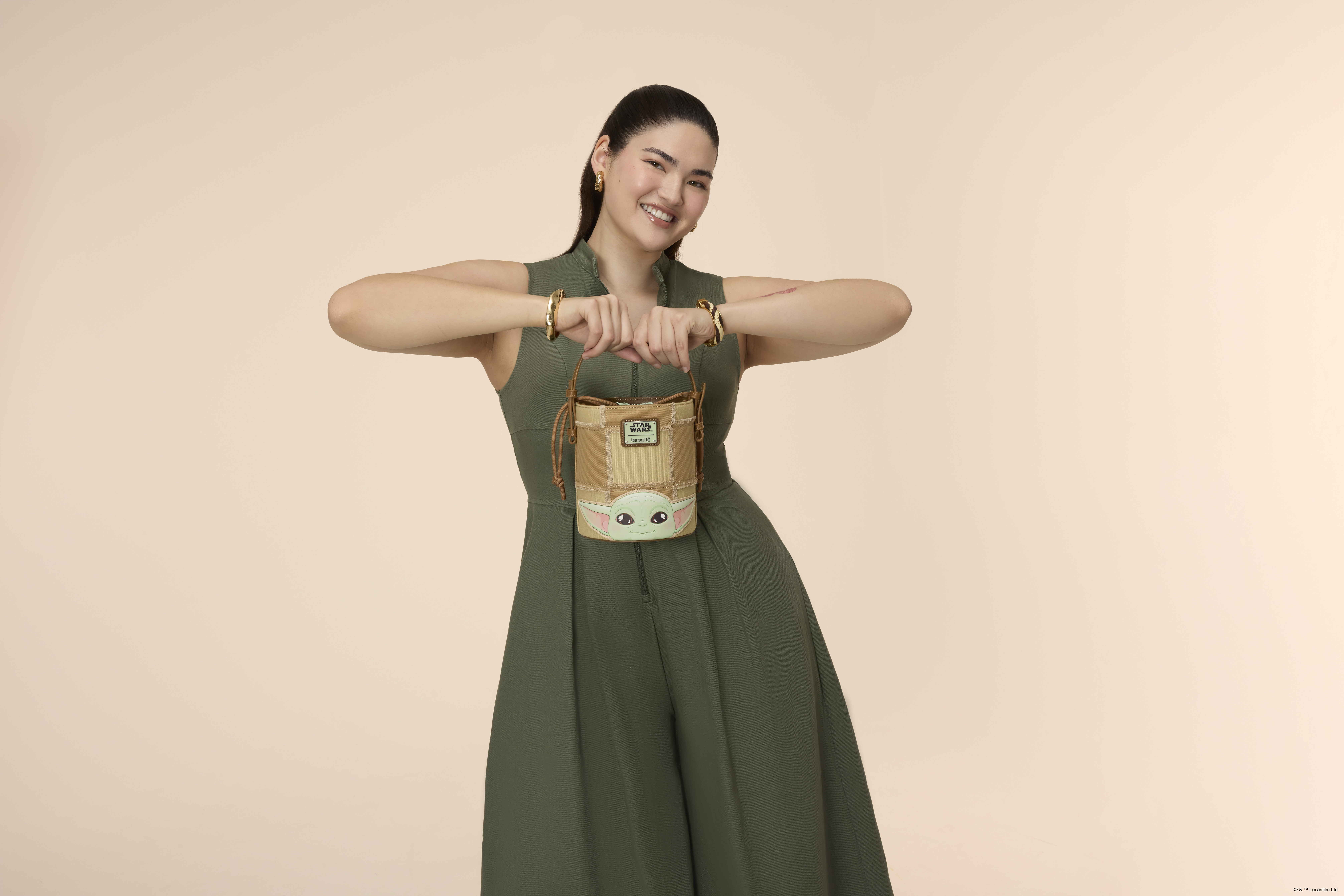 A woman holding a Loungefly bucket crossbody bag in a pink environment