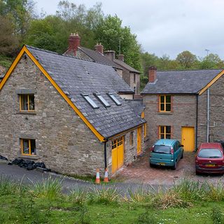 stone cottage with cars and road