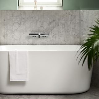 a bathroom with a bathtub, grey tiles and green walls