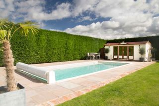 Outdoor pool with pool house by Mermaid Pools